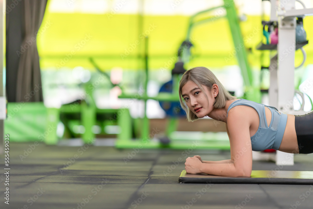 Strong young woman doing push-ups in gym. Fit female exercising in health club. Strong young woman doing push-ups in gym. Fit female exercising in health club.