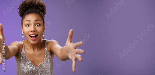 Amused elegant woman looking desire extend arms widen eyes impressed gasping extend arms towards camera hug give embrace cannot resist temptetion standing blue background photo