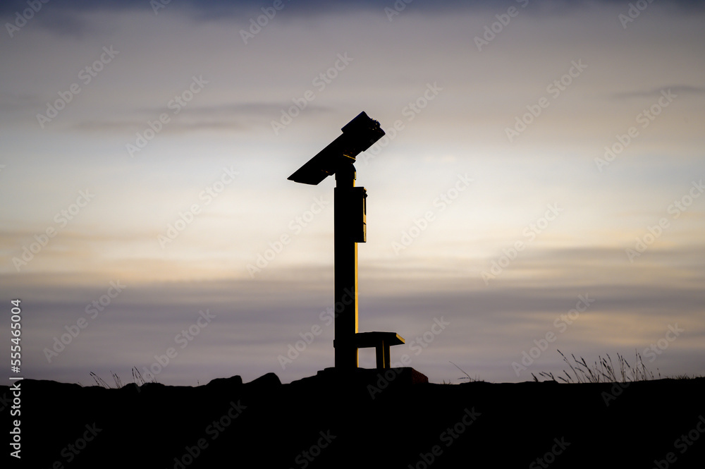 Low Key style photo of coin operated public binoculars or telescope at dawn