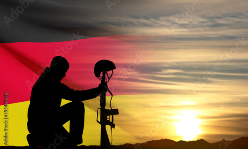 Silhouette of soldier kneeling down on a background of sunset and Germany flag. Greeting card for National Holidays. EPS10 vector