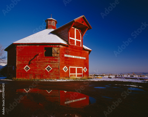 Agriculture - Crossed Sabres Ranch red octagonal barn with snow on the ground around it and a reflection in a puddle / Joseph, Oregon, USA. photo