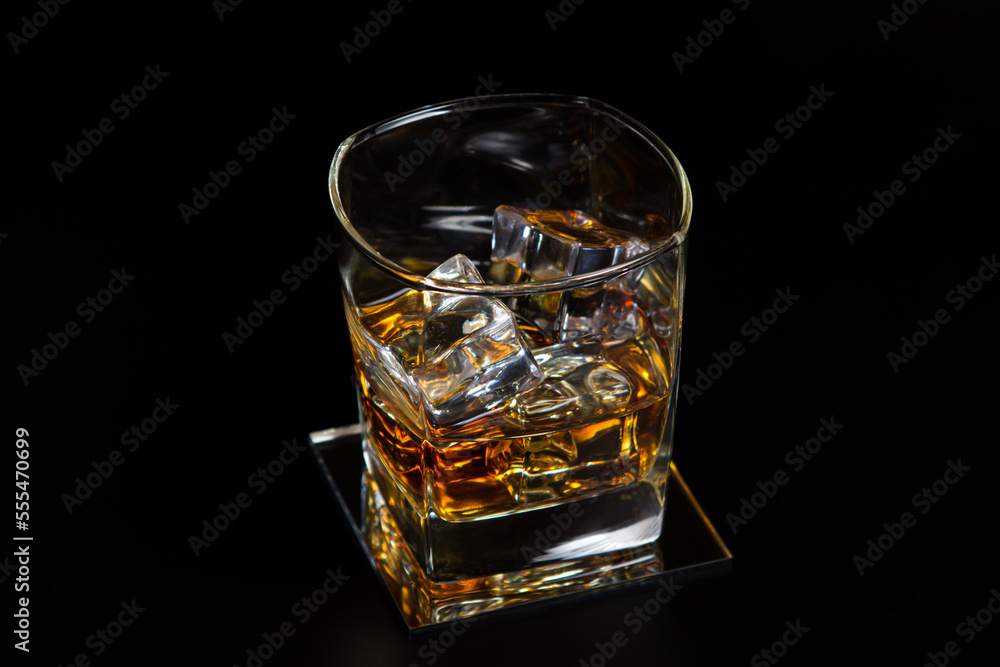 Glass of whiskey with ice on a black background. Strong alcoholic drink