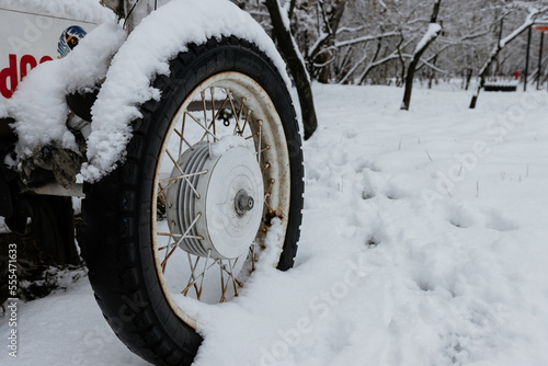 Old wheel with spokes in the snow. Close up vintage white car wheel over snow cover in winter time