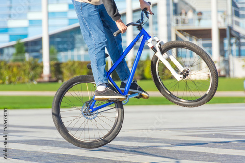 Fototapeta Naklejka Na Ścianę i Meble -  Cyclist jumps on a bicycle on a playground in a city park, performing tricks.