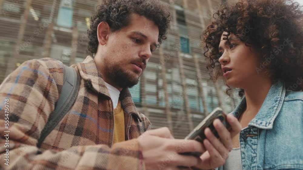 Close-up of student couple talking and using smartphone Close-up of student couple talking and using smartphone