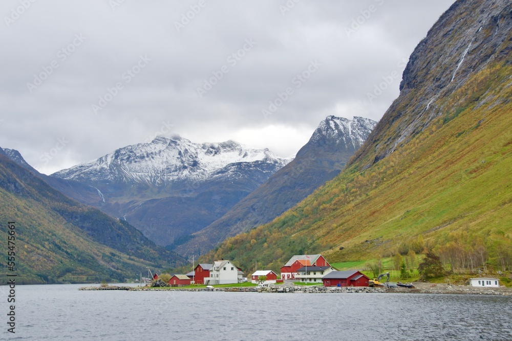Village of Urke in Norangsfjorden among snow capped mountains and autumn foliage in Norway