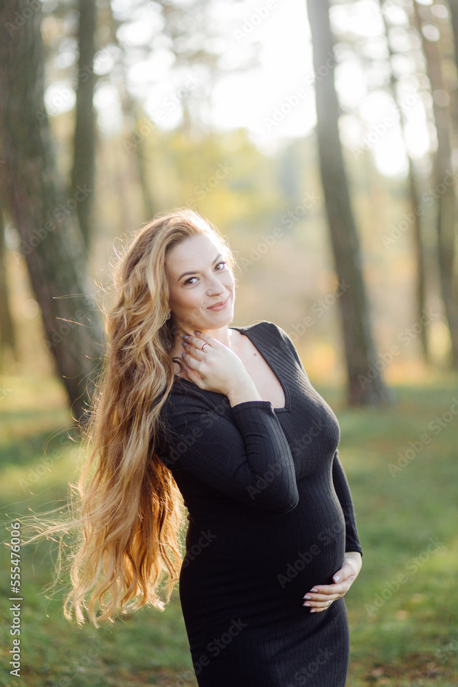 Pregnant happy young woman walking outdoors in forest Pregnant happy young woman walking outdoors in forest
