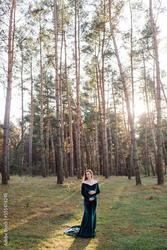 Pregnant happy young woman walking outdoors in forest