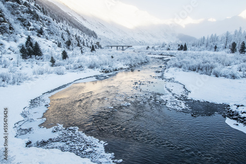 River flowing through a snowy, mountainous landscape at sunrise; Alaska, United States of America