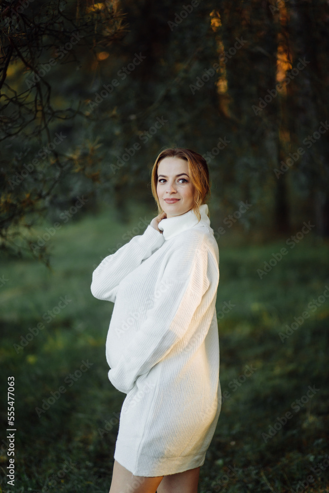 Pregnant happy young woman walking outdoors in forest