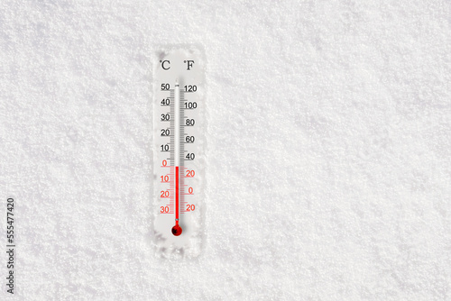 White celsius and fahrenheit scale thermometer in snow. Ambient temperature zero degrees celsius