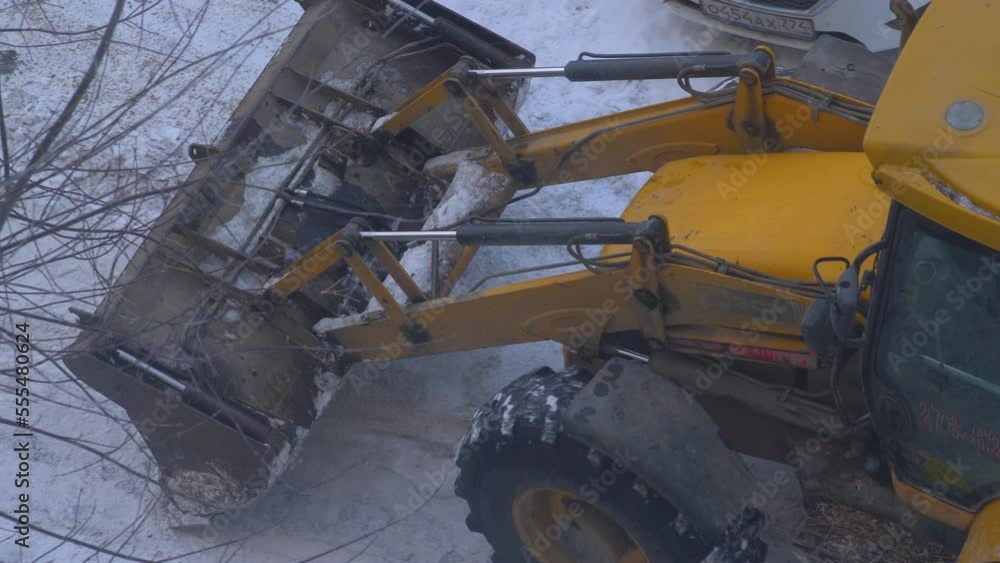 bulldozer with a bucket cleans snow from city streets on a winter day. municipal services clean the snow in the city. tractor cleans snow from the sidewalks in the quarter. bulldozer with a bucket cleans snow from city streets on a winter day. municipal services clean the snow in the city. tractor cleans snow from the sidewalks in the quarter.