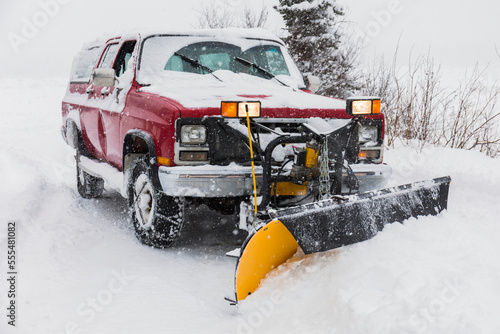 A truck with a plow clears snow from a driveway during blizzard conditions in the Alaska Range; Alaska, United States of America photo