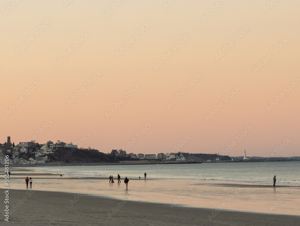 people walking on the beach at sunset