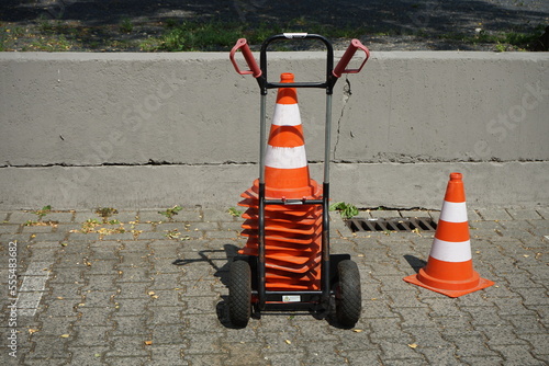 Sackkarre mit Lübecker Hütchen, Pylon oder Verkehrsleitkegel auf dem Parkplatz mit Verbundpflaster im Sommer bei Sonnenschein in der Klassikstadt im Stadtteil Fechenheim in Frankfurt am Main in Hessen photo