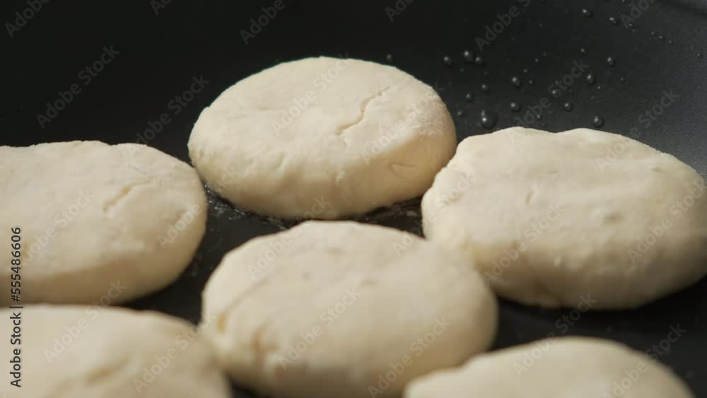 the cook turns over the cheesecakes that are fried in a frying pan. women's hands make syrniki. cheesecakes, syrniki are fried in a frying pan the cook turns over the cheesecakes that are fried in a frying pan. women's hands make syrniki. cheesecakes, syrniki are fried in a frying pan
