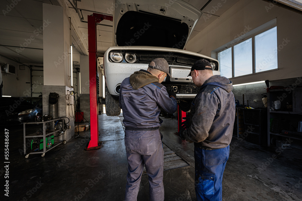 Two mechanic in service repair station calibrate the distronic in muscle car in lift. Two mechanic in service repair station calibrate the distronic in muscle car in lift.
