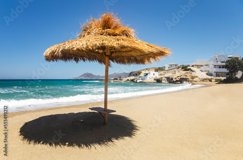 Thatch shelter casting shade onto the beach; Milos, Greece