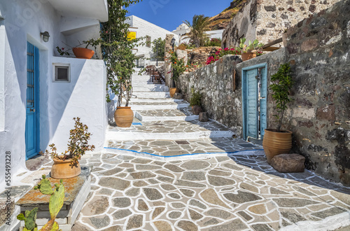 Traditional houses with white facade and colourful accents along a stone walkway; Milos, Greece photo