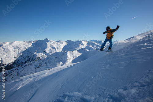 Boarder on a snowboard jumping on a beautiful day in the big mountains, winter in Alps