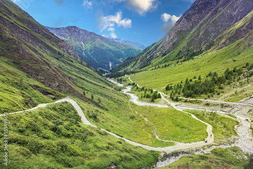 The mountain road winds through a beautiful green valley among the Grossglockner mountains