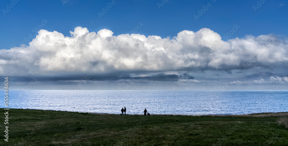 People stand on the beach enjoying the coast and the awe inspiring cloud formations in the distance; South Shields, Tyne and Wear, England People stand on the beach enjoying the coast and the awe inspiring cloud formations in the distance; South Shields, Tyne and Wear, England
