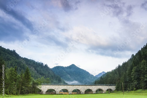 Old stone railway viaduct bridge crossing a grass field in a valley in the Austrian Alps; Wildalpen, Landl, Austria photo