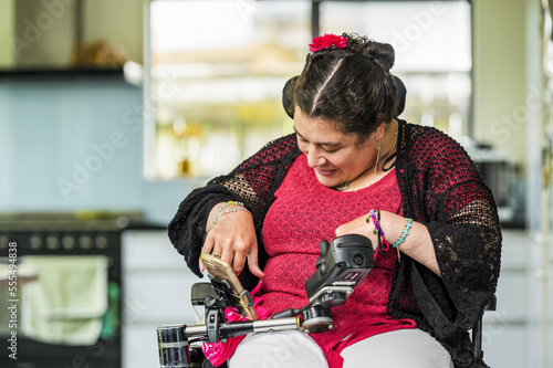 Maori woman with Cerebral Palsy in a wheelchair using a smart phone; Wellington, New Zealand photo