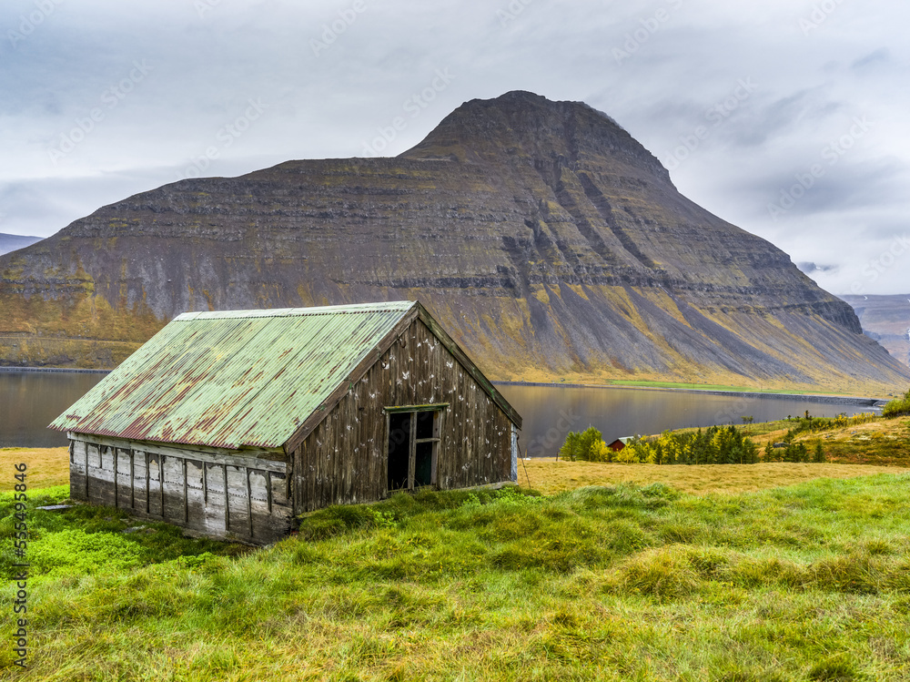 Weathered building on the water's edge of a fjord in Northwestern Iceland in the municipality of Isafjarourbaer; Isafjarourbaer, Westfjords Region, Iceland Weathered building on the water's edge of a fjord in Northwestern Iceland in the municipality of Isafjarourbaer; Isafjarourbaer, Westfjords Region, Iceland
