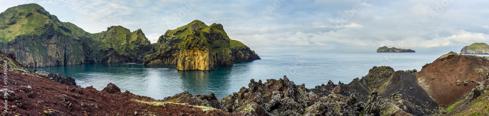 Rugged rock and cliffs along the coastline of the island of Heimaey, a part of an archipelago along the Southern coast of Iceland; Vestmannaeyjar, Southern Region, Iceland Rugged rock and cliffs along the coastline of the island of Heimaey, a part of an archipelago along the Southern coast of Iceland; Vestmannaeyjar, Southern Region, Iceland