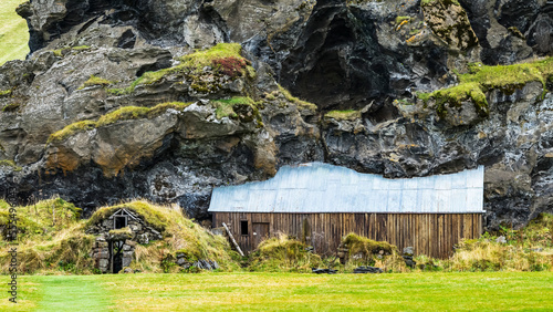 Barn and shed built into a rocky mountainside, now overgrown with grass; Rangarping eystra, Southern Region, Iceland photo