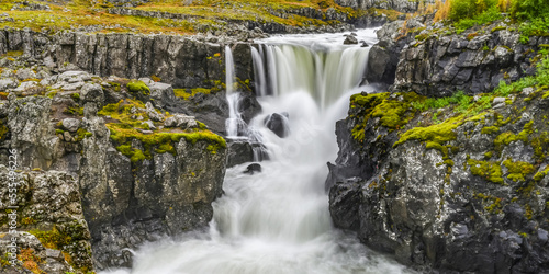 Waterfall and rushing river on a rugged landscape in Eastern Iceland; Djupivogur, Eastern Region, Iceland photo