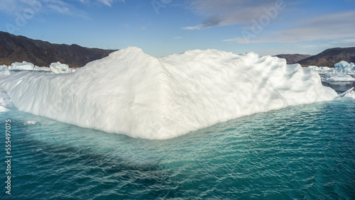 A large wedge iceberg along the coast of Greenland in bright blue water; Sermersooq, Greenland photo