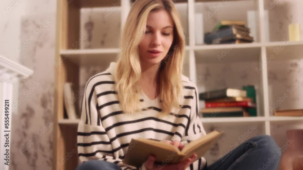Dreamy soft shot of young charming blond woman reading book story in cozy living room Attractive female enjoying leisure time weekend with literature novel at home alone Dreamy soft shot of young charming blond woman reading book story in cozy living room Attractive female enjoying leisure time weekend with literature novel at home alone