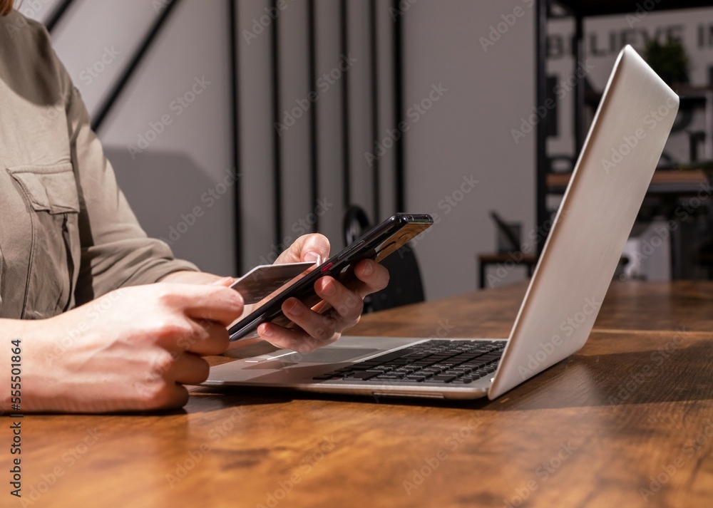 Online payment concept. Hands with bank debit card, mobile phone and laptop, making purchase, shopping, buying through internet Online payment concept. Hands with bank debit card, mobile phone and laptop, making purchase, shopping, buying through internet
