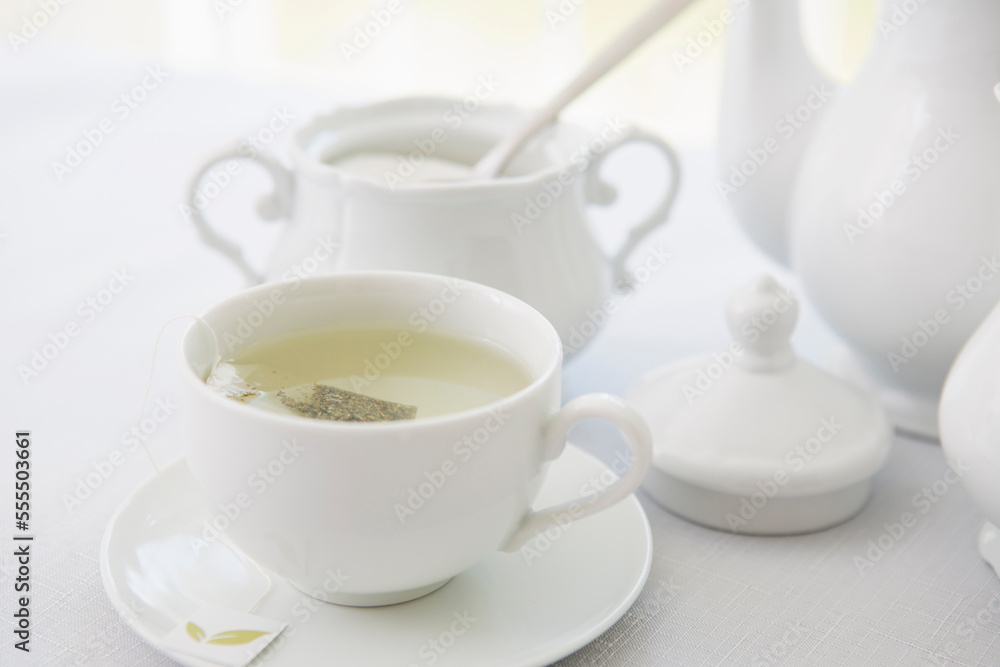 Cup of tea in porcelain white teacup with saucer, sugar bowl, and teapot, studio shot Cup of tea in porcelain white teacup with saucer, sugar bowl, and teapot, studio shot