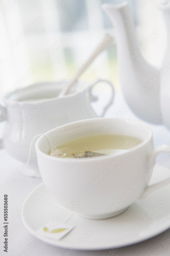 Cup of tea in porcelain white teacup with saucer, sugar bowl, and teapot, studio shot Cup of tea in porcelain white teacup with saucer, sugar bowl, and teapot, studio shot