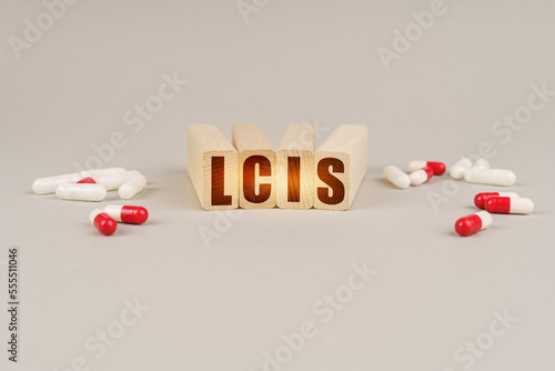 On a gray surface are pills and a red wooden block with the inscription - LCIS photo