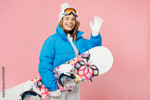 Side view happy smiling snowboarder woman wear blue suit goggles mask hat ski padded jacket waving hand isolated on plain pastel pink background. Winter extreme sport hobby weekend trip relax concept. #555513087