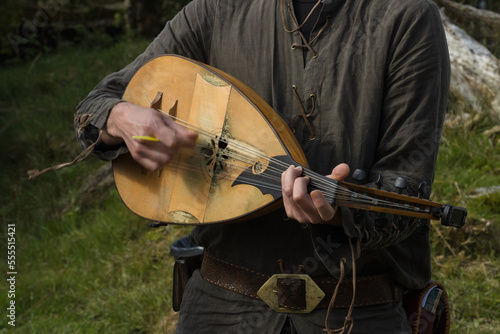 Man dressed in a garb playing a mediveal string instrument called Lute. photo