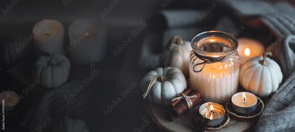 Autumn home composition with aromatic candle, dry citrus, cinnamon, anise. Aromatherapy on a grey fall morning, atmosphere of cosiness and relax. Wooden background close up copy space banner