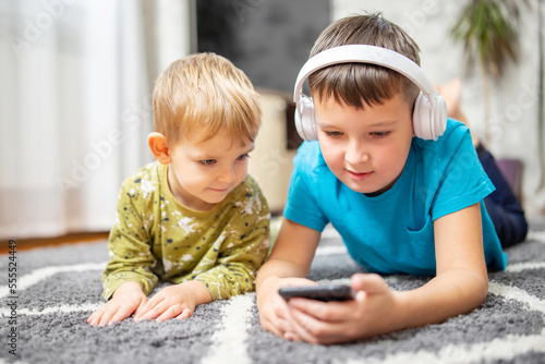 Two children watching smart phone, happy kids using smartphones together