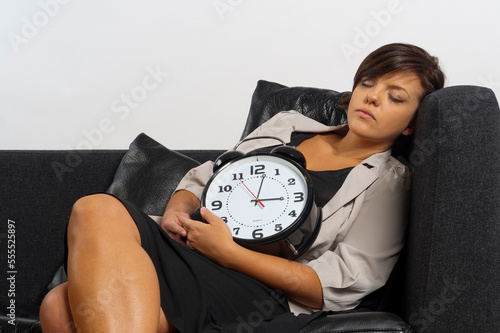 Portrait of Mid-Adult Woman Sleeping on Sofa and holding Alarm Clock photo