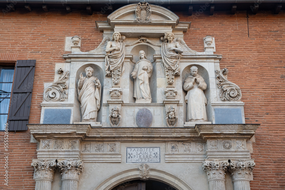 View of ancient stone carving depicting Jesus, St Peter, a carthusian monk and angels above entrance gate to St Pierre des Chartreux church, Toulouse, France