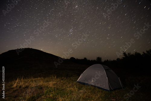 Tourist tent on a hill overlooking the night sky