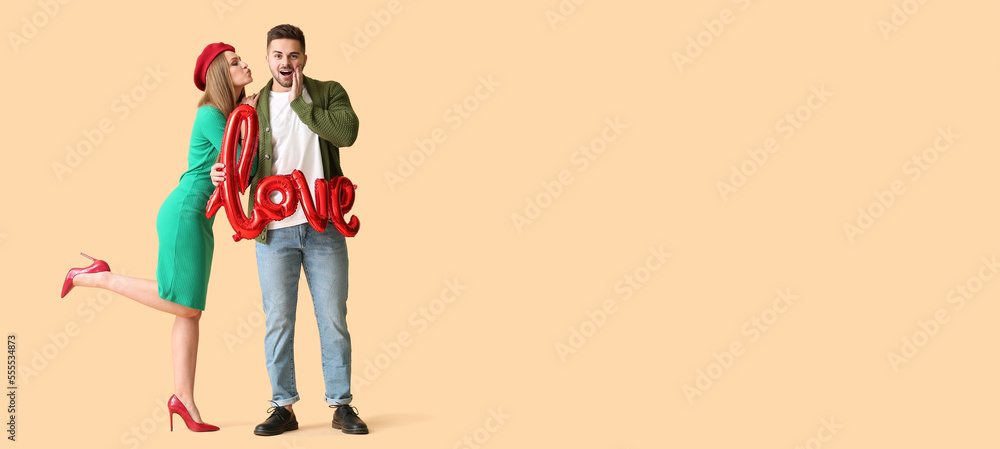 Happy young couple holding air balloon in shape of word LOVE on beige background with space for text. Valentine's Day celebration Happy young couple holding air balloon in shape of word LOVE on beige background with space for text. Valentine's Day celebration