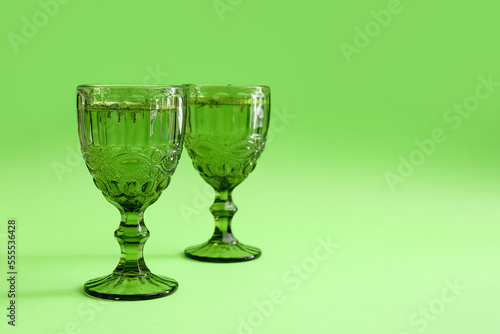 Glasses of cocktail on green background