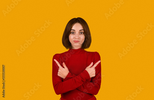 Confused pretty brunette lady pointing at copy space
