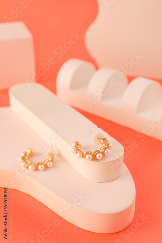 Stand with pearl earrings on color background