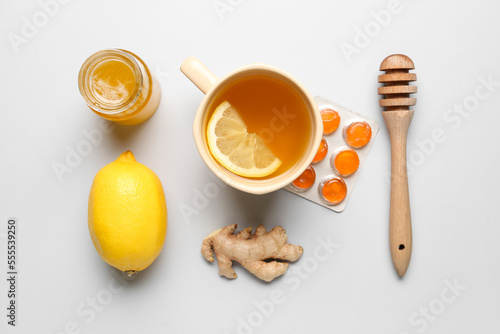 Pills for sore throat, cup of tea, lemon, ginger and honey on light background © Pixel-Shot